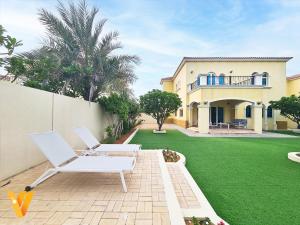 迪拜Luxury 3BR Private Villa and Elaborate Gardens的一个带两把白色椅子的院子和房子