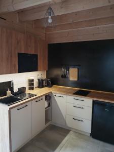 尼彻兹SOSNOWY KLIFF的厨房配有白色橱柜和黑色墙壁