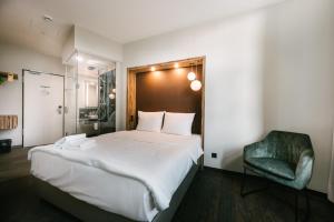 莱比锡莱比锡市旅行24酒店的一间卧室配有一张大床和一张绿色椅子