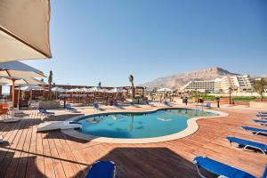 艾因苏赫纳Tolip Resort El Galala Majestic的一个带椅子的游泳池,后方是一座山。