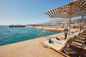 艾因苏赫纳Tolip Resort El Galala Majestic的水边的一排椅子和遮阳伞
