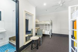 悉尼London Plane Backpackers的客房设有镜子、桌子和双层床。