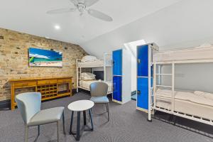 悉尼London Plane Backpackers的配有双层床和桌椅的房间