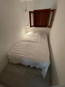 海滨圣玛丽Appartement bord de mer的窗户客房内的一张白色小床