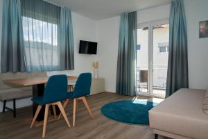 玛丽亚韦尔特Appartements am See的客厅配有桌子和蓝色椅子