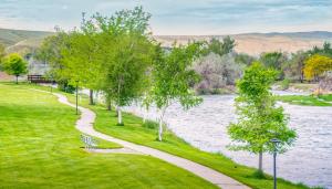 瑟莫波利斯Amenity-Rich Summer Fun, You'll Love It, Discover An Exceptional Wyoming Stay, Thermopolis River Walk Home at Hot Springs State Park, Where The Fisherman Stay, Available June 6的一条小径,一条有树木和长凳的河流旁