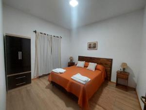 卡法亚特Departamento Cafayate的一间卧室配有带橙色床单的床铺和电视。