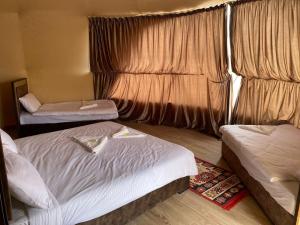 瓦迪拉姆Al Rifi Luxury Camp的酒店客房设有两张床和窗户。