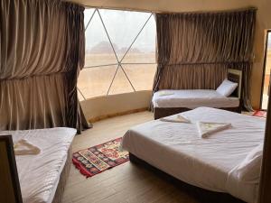 瓦迪拉姆Al Rifi Luxury Camp的酒店客房设有两张床和大窗户。