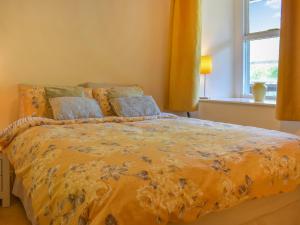 科克茅斯Hatters Croft的一间卧室配有一张带黄色棉被的床和窗户