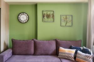 拉里萨Το πιο ευχάριστο διαμέρισμα της πόλης的客厅配有紫色沙发和时钟
