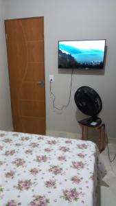 卡鲁阿鲁Casa Confortável的一间卧室配有一张床和一台平面电视