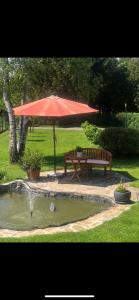 穆勒克Ferienwohnung Eva的池塘旁的野餐桌和红伞