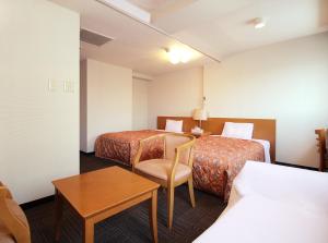 东村山市ビジネスホテルマーキュリー（ロイヤルイングループ）的酒店客房设有两张床和一张桌子。