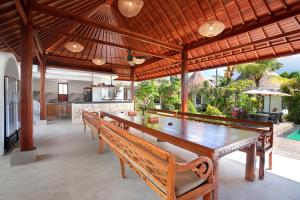 乌鲁瓦图巴里坎达西尔酒店的用餐室设有一张大木桌和长凳