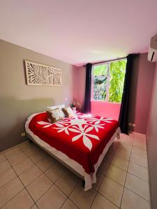 AtiueVahinerii Cosy Apt Tahiti的卧室配有红色和白色的床,设有窗户