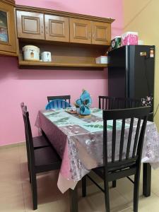 波德申EQ Malay Modest Homestay Port Dickson的一张带粉红色墙壁和黑色冰箱的餐桌