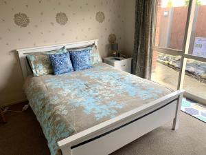 北帕默斯顿KG Ensuite的一间卧室配有一张带蓝色枕头的床和一扇窗户。