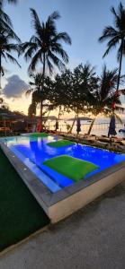 班拉克海滩苏梅岛码头海滨度假酒店的一座拥有蓝色海水和棕榈树的大型游泳池
