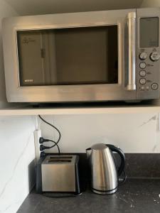 北帕默斯顿KG Studio的架子上的微波炉,配有咖啡壶和烤面包机