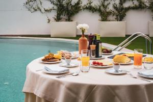 阿尔贝罗贝洛Hotel Majesty Alberobello的一张桌子,旁边是游泳池,摆放着食物和饮料