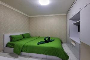 TekoB Nature Aeropolis Inn的一间卧室配有一张绿色的床和黑色天鹅雕像