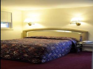 菲什基尔乡村汽车旅馆的卧室内的一张床位,墙上有两盏灯