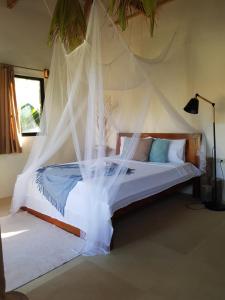 卢纳将军城Tropical Bungalows-Siargao的一间卧室配有一张带蚊帐的床