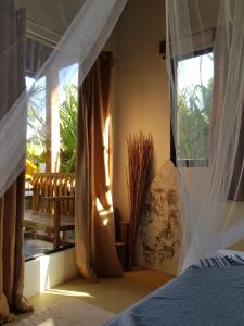 卢纳将军城Tropical Bungalows-Siargao的一间卧室配有带窗帘的床和窗户
