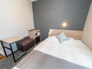 仙台Super Hotel Premier Sendai Kokubuncho Tennenonsen的一间小卧室,配有一张床和一把椅子