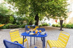 尼斯L'Abeille - Boutique Apartments的一张蓝色桌子,上面有黄色椅子和食物