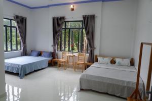 Hồ ÐáHương Tràm的一间卧室配有两张床和一张桌子及椅子