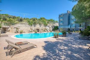 切什梅AEGEAN Apartments - Marina & Chios Island View的一座带椅子的游泳池以及一座建筑