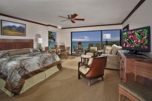 拉海纳纳普里凯海滩度假酒店的一间卧室配有一张床,客厅配有电视