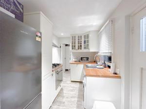 悉尼Pyrnmont Terrace & Townhouse的厨房配有白色橱柜和不锈钢冰箱