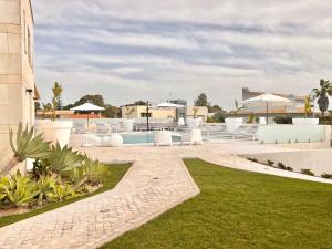 特罗亚Soltroia Beach Court Villa的一座带白色家具和草地的度假村游泳池