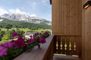 科尔蒂纳丹佩佐Camina Suite and Spa的阳台享有鲜花和山脉的背景