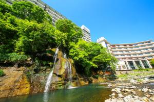 那须盐原市Ooedo Onsen Monogatari Hotel New Shiobara的河中的瀑布,有建筑背景
