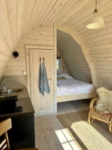 Belt-SchutslootLODGE, een super knus tiny house, nabij vaarwater en haven!的木制客房内的一间卧室,配有一张床