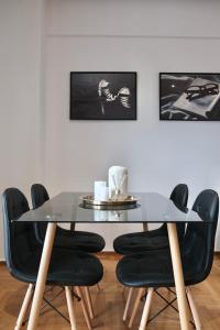 比雷埃夫斯SynPiraeus Apartments & Studios的一间设有玻璃桌和黑色椅子的用餐室
