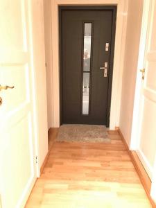 卑尔根Apartment in Åsane的走廊上设有黑色的门,铺有木地板