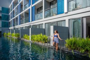 芭东海滩Hotel Indigo Phuket Patong, an IHG Hotel的站在水面上站在建筑物前的妇女