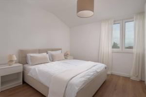SmokovićSpacious and fully equipped apartment near Zadar的白色的卧室设有白色的床和窗户。