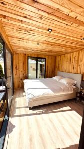 MatslootLuxe Tiny House bij het Leekstermeer的卧室设有一张木制天花板上的大床