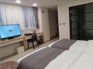 华城市Hotel Ciel Dongtan的酒店客房配有一张床和一张书桌及一台电视