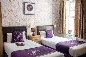 诺里奇Revado Hotel的两张位于酒店客房的床铺,配有紫色床单