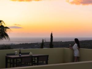 马鲁拉斯Mela Villas的站在阳台上欣赏日落的女人