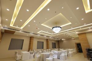 巴特那Hotel Sharda Residency的宴会厅配有白色的桌椅和吊灯