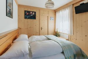 圣维托-迪卡多雷蒙大拿州罗坎达宾馆的卧室设有木墙和一张带白色枕头的床。