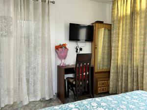 钱德加尔Cozy Nest - Garden Facing Apartment with Kitchen的一间卧室配有床、电视和窗帘